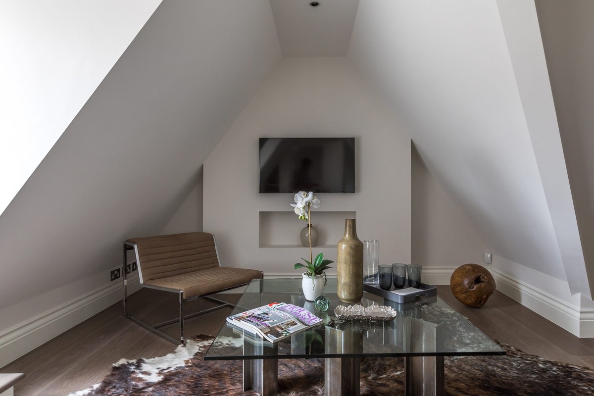 Attic lounge with white walls and a glass coffee table