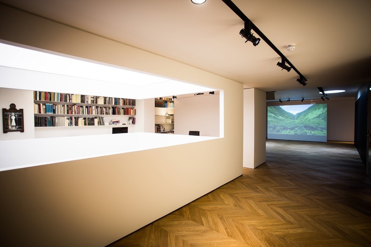 White-walled gallery with a projection screen at the far end