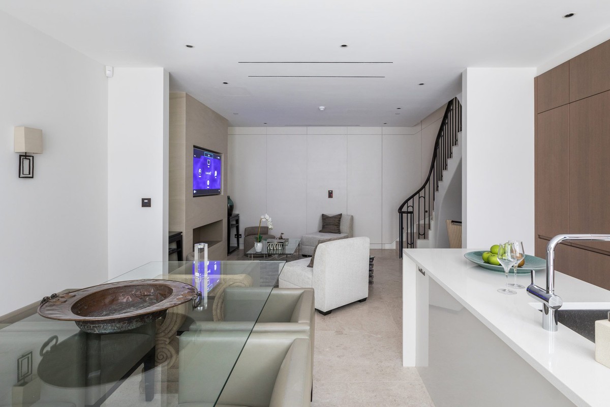 Open-plan living room with a white kitchen and staircase