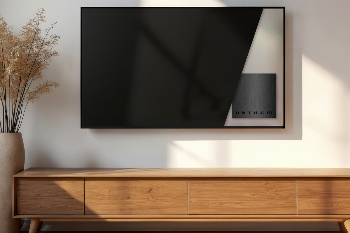 Wandmontierter Fernseher über einem Sideboard aus Holz, mit einem kompakten Gerät hinter dem Bildschirm