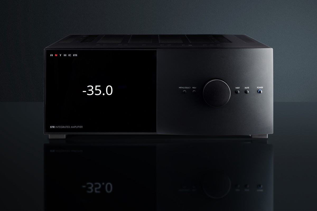 Frontale di un amplificatore integrato nero con grande display TFT e manopola del volume, su una superficie scura riflettente