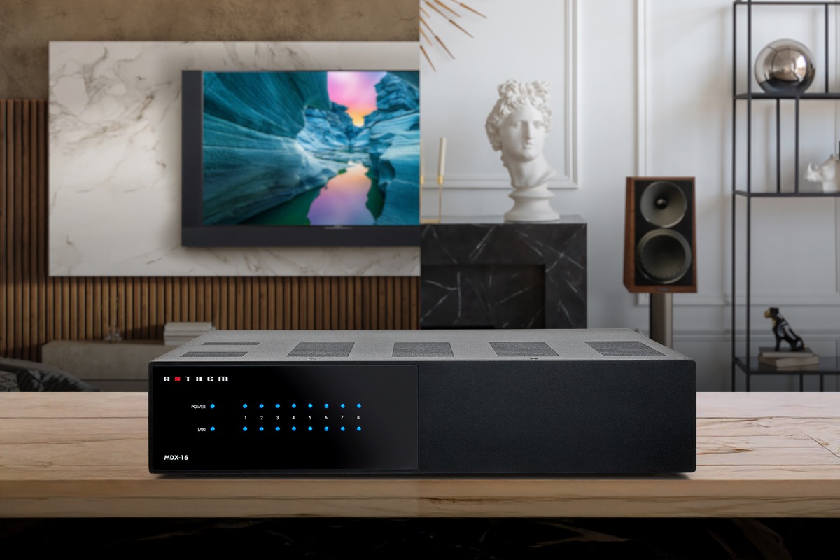Multiroom-Verstärker auf einem Holzmöbel vor einem Wohnzimmer mit Fernseher
