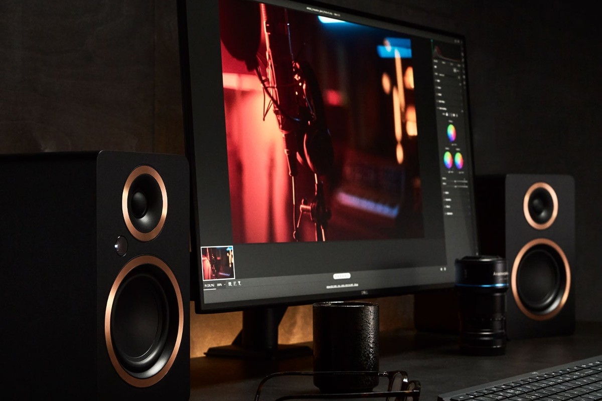 Due diffusori neri ai lati del monitor di un computer su una scrivania