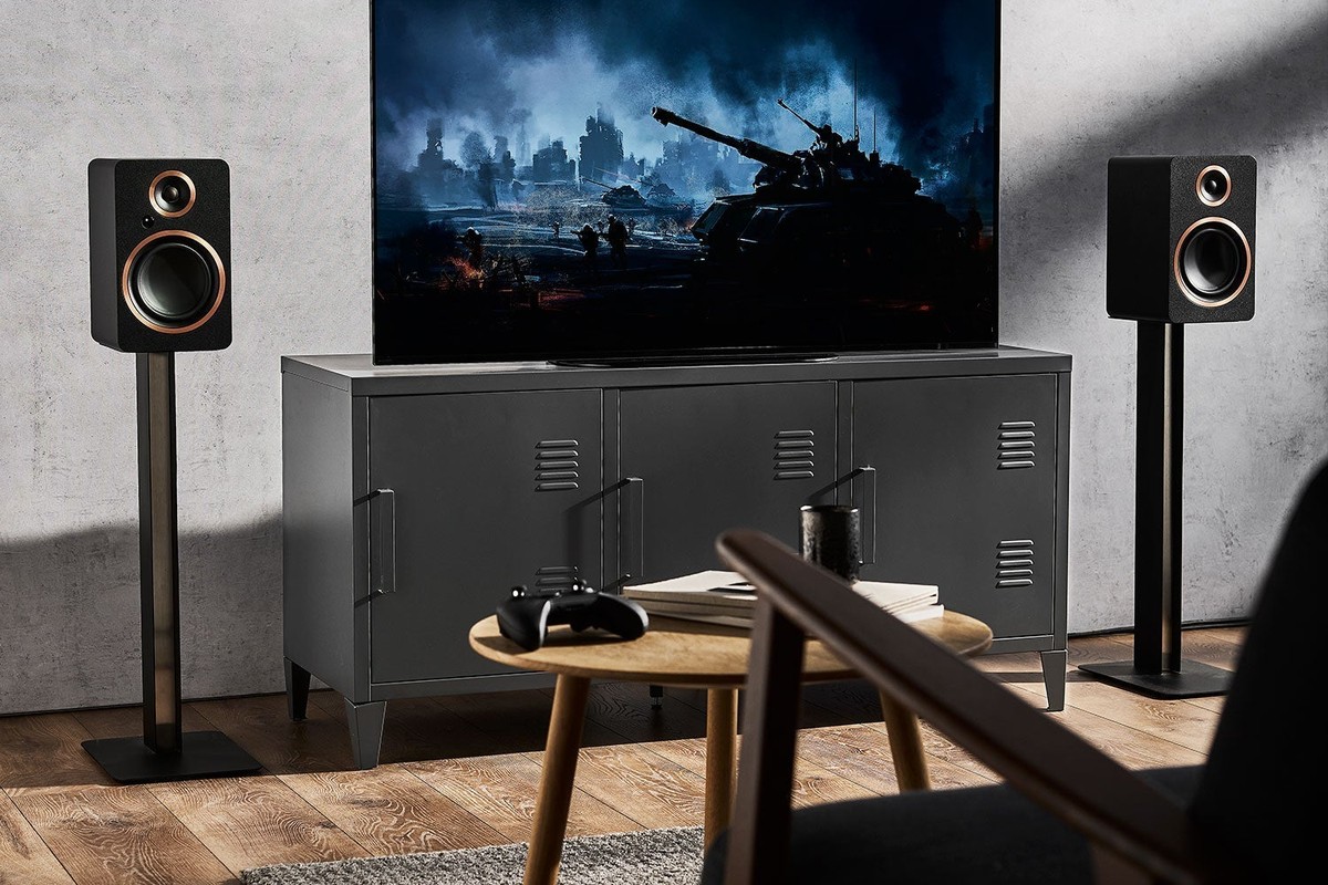 Coppia di diffusori neri su supporti ai lati di un televisore