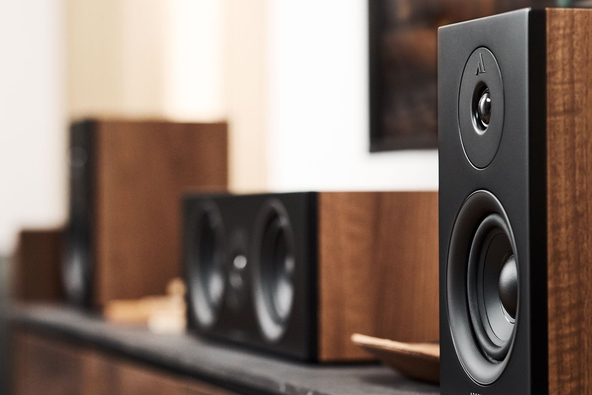 Primo piano di un diffusore in finitura noce con frontale nero, accanto a un canale centrale