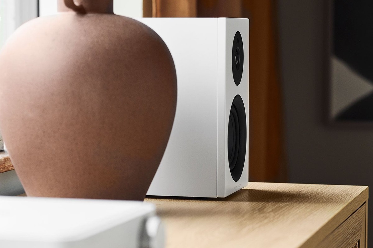 Diffusore bianco su un mobile in legno chiaro, dietro un vaso in terracotta