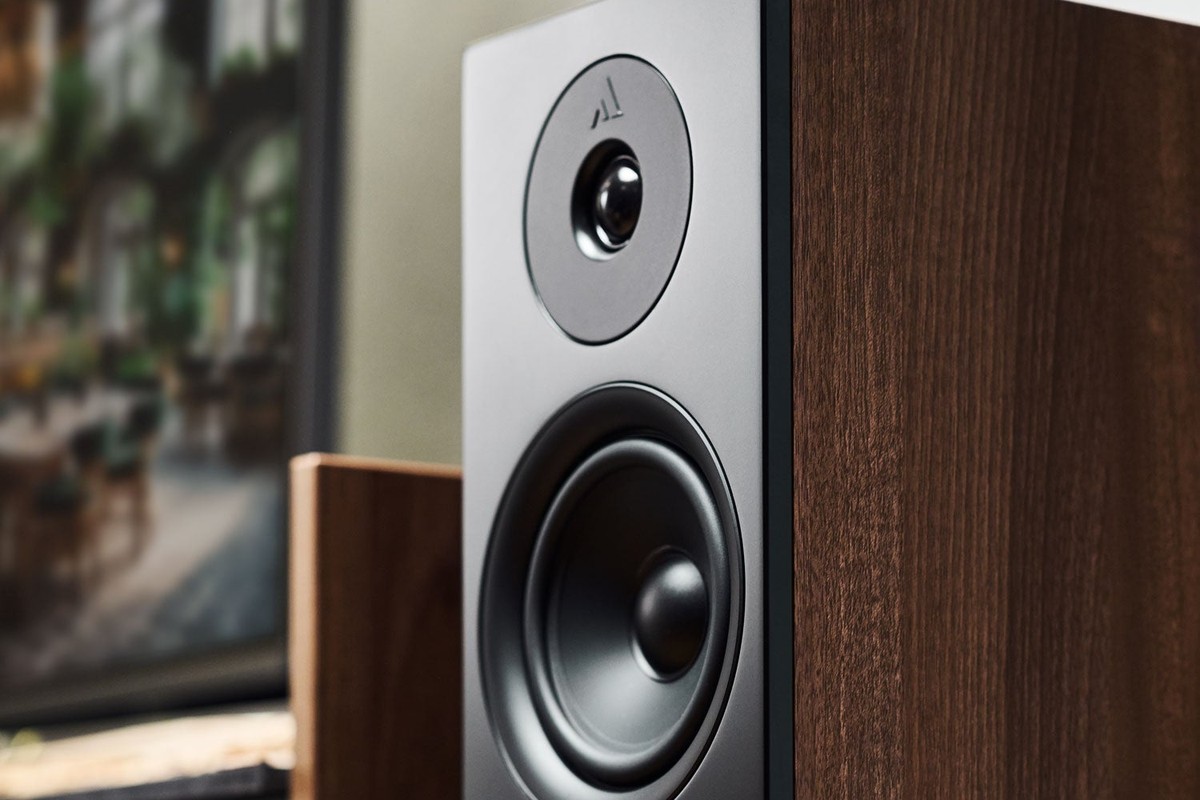 Primo piano di un diffusore da pavimento in noce con frontale nero, tweeter e woofer