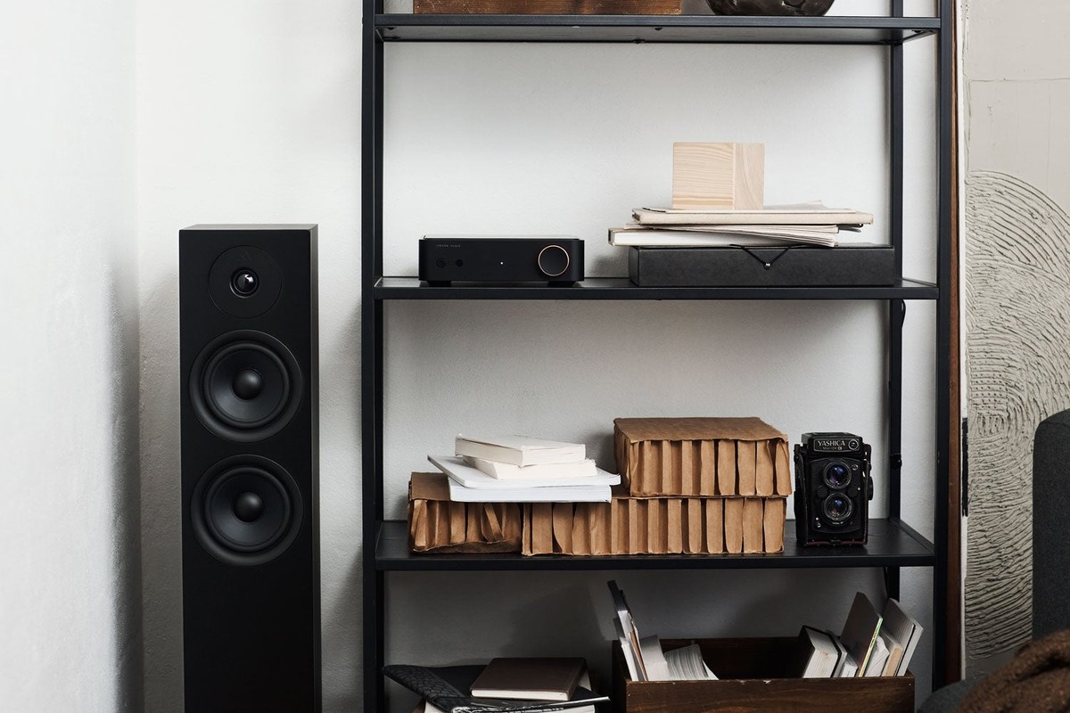 Diffusore da pavimento nero accanto a una scaffalatura in metallo con un amplificatore