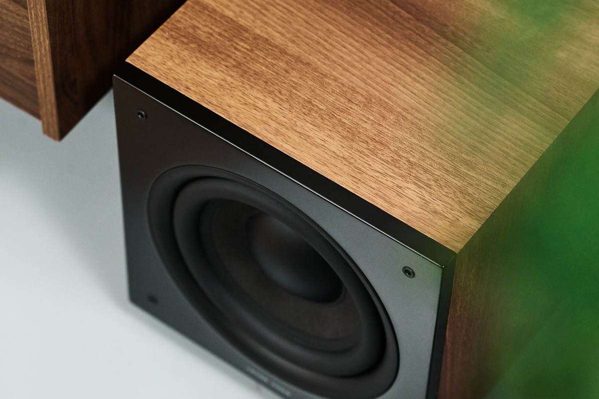 Close-up of a black bass driver set into a walnut-finish cabinet