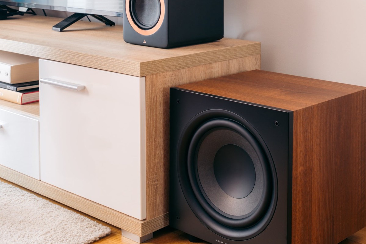 Caisson finition noyer sous un meuble TV, à côté d'une enceinte compacte