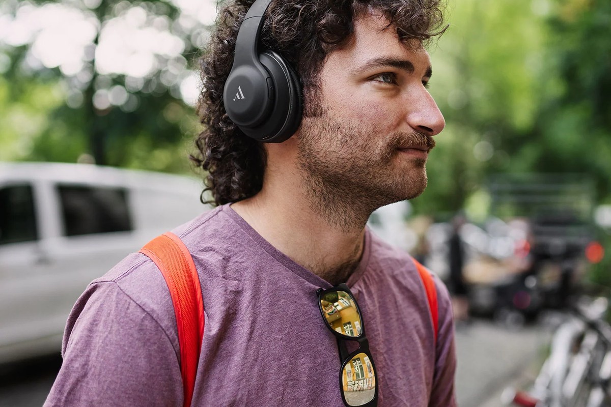Uomo che ascolta musica con cuffie nere in una strada alberata