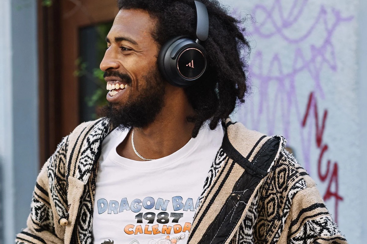 Uomo sorridente che indossa cuffie nere per strada