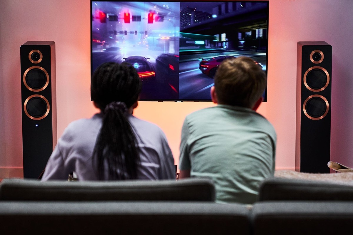 Due bambini davanti a un televisore affiancato da due diffusori neri