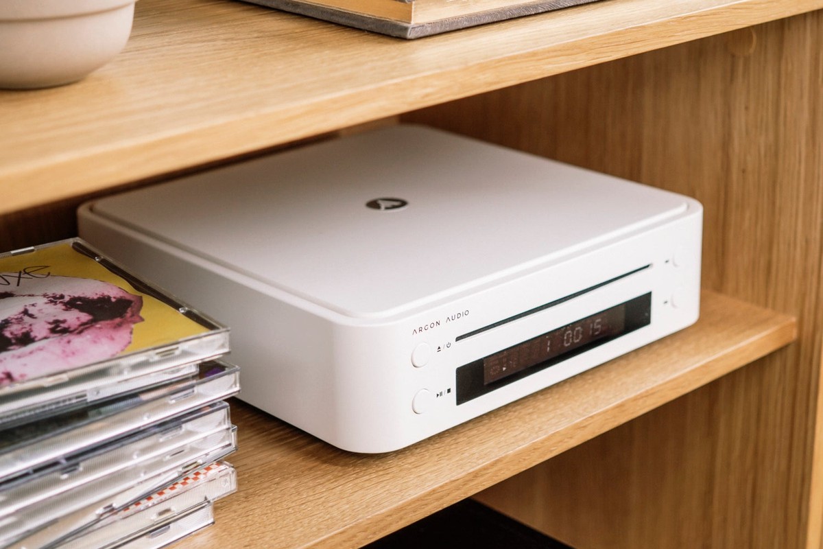Lettore CD bianco su una mensola con custodie di CD