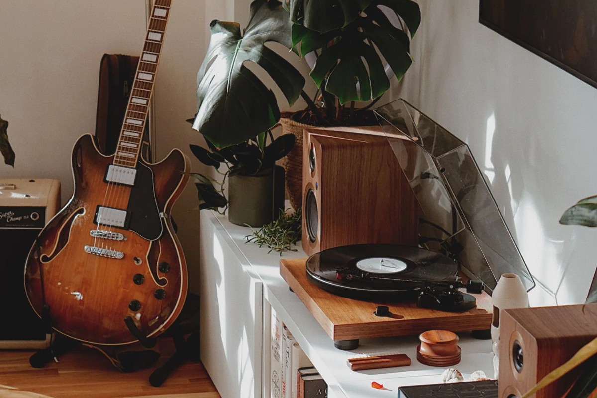 Platine en noyer sur un meuble blanc, près d'une guitare et de plantes