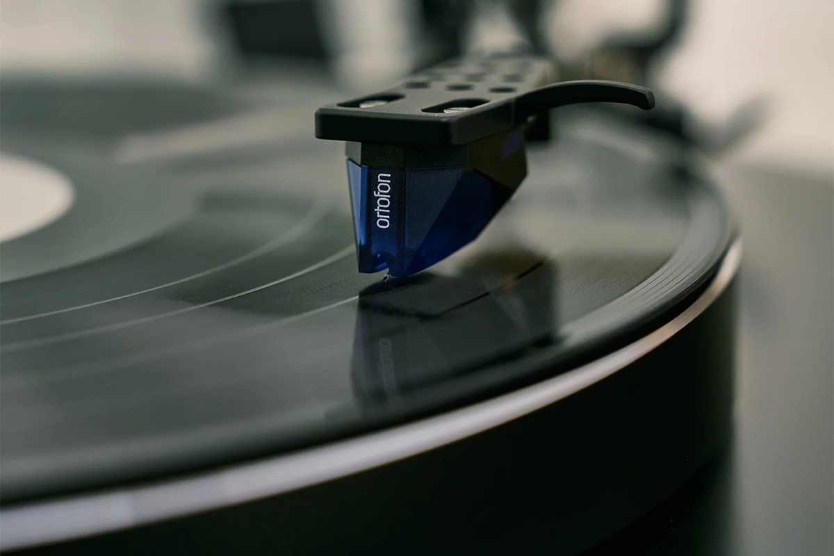 Close-up of a blue cartridge resting on a record