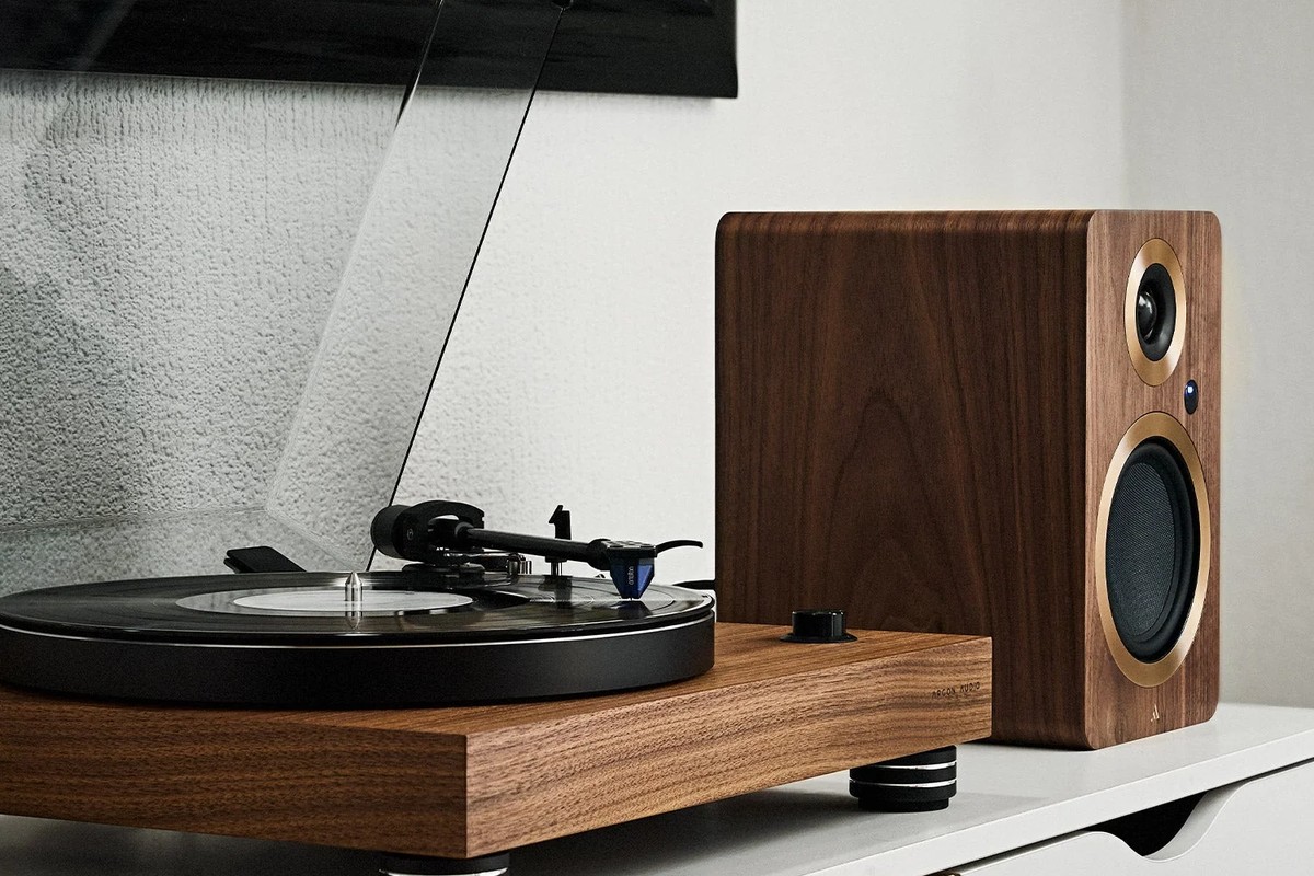 Walnut turntable next to a wooden speaker on a white cabinet