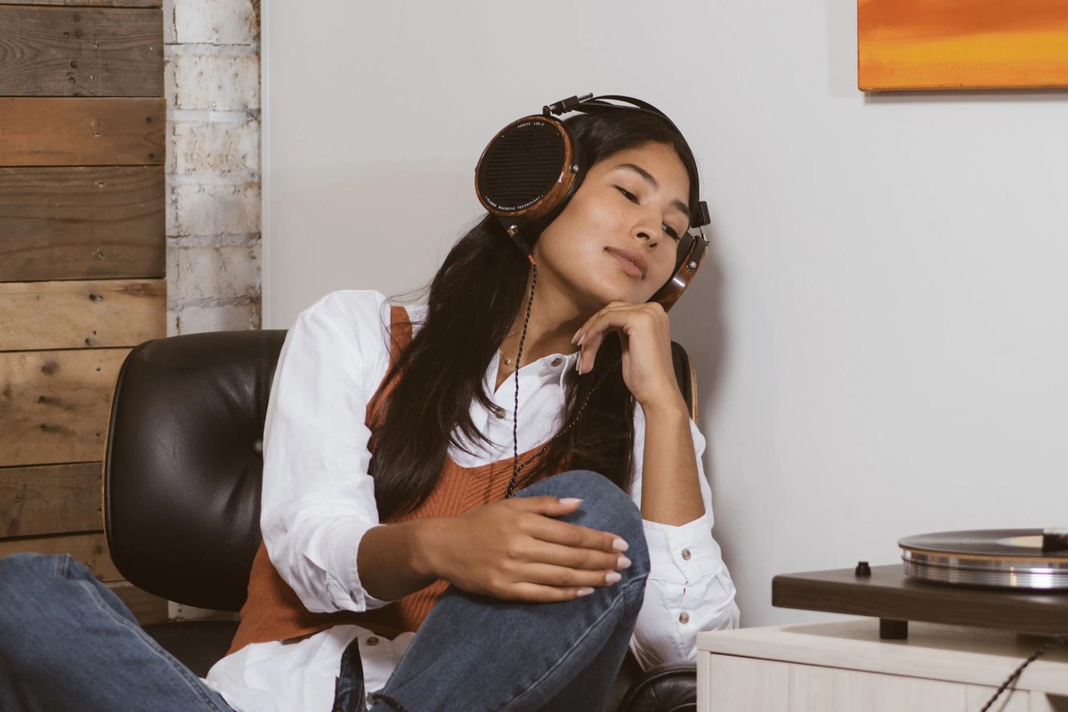 Auditrice installée dans un fauteuil, casque sur les oreilles, devant une platine vinyle
