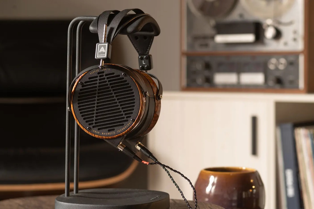 Cuffie circumaurali appoggiate sul supporto, in un ambiente con giradischi ed elementi hi-fi vintage