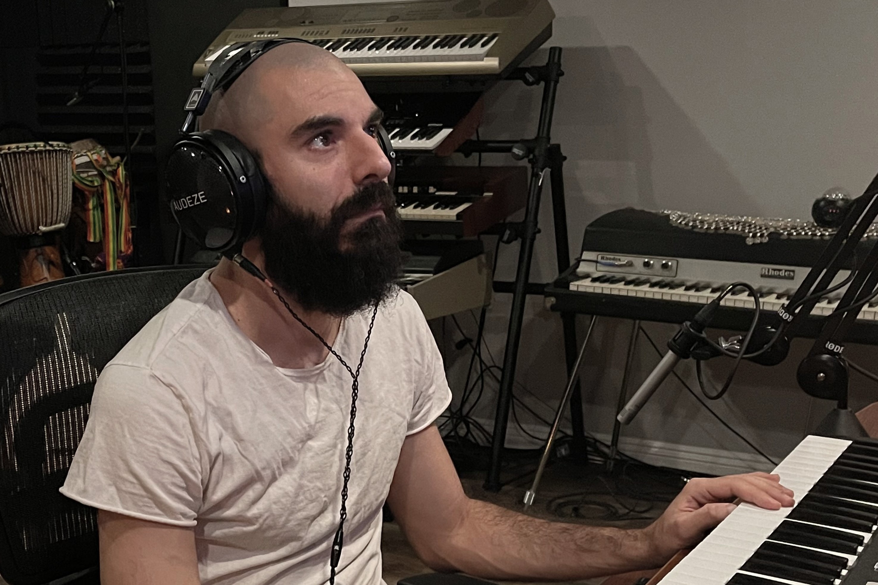 Musiker im Studio, geschlossener Kopfhörer auf den Ohren, Hand auf einer Tastatur