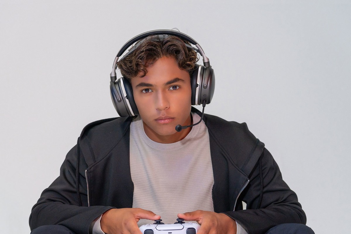 Giocatore che indossa le cuffie, controller PlayStation in mano