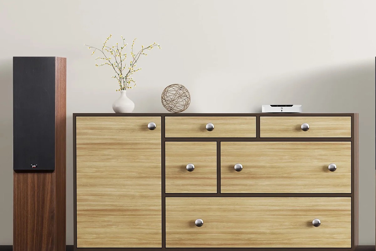 Floorstanding speaker and light wooden cabinet in a living room, unit sitting on the chest of drawers