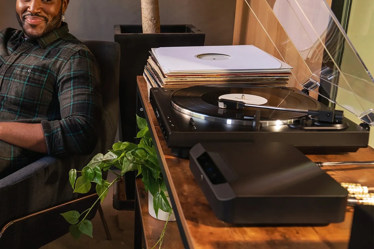 Turntable on a coffee table, the unit connected below, a person seated nearby