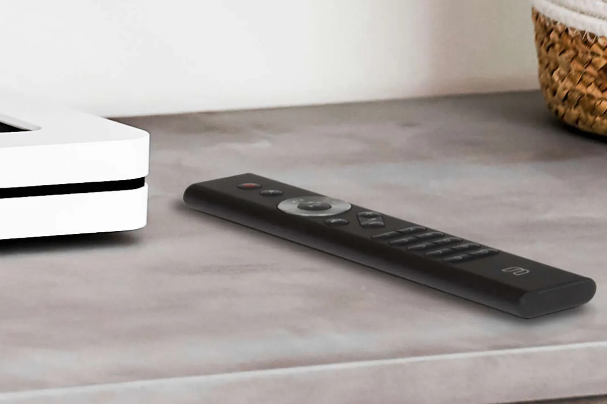 Télécommande posée près d'un lecteur réseau blanc sur un meuble