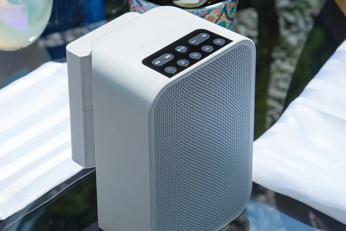 Enceinte blanche équipée de son pack batterie, posée en extérieur