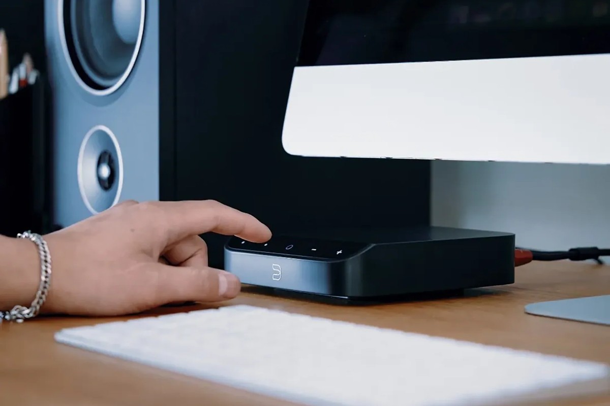 Postazione di lavoro, apparecchio collegato a diffusori da monitor, una mano sul telaio