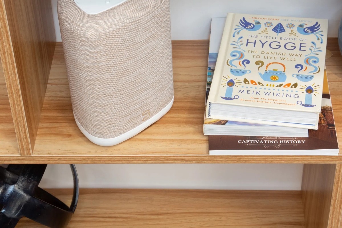 Vue rapprochée de l'enceinte sur une étagère, à côté de livres