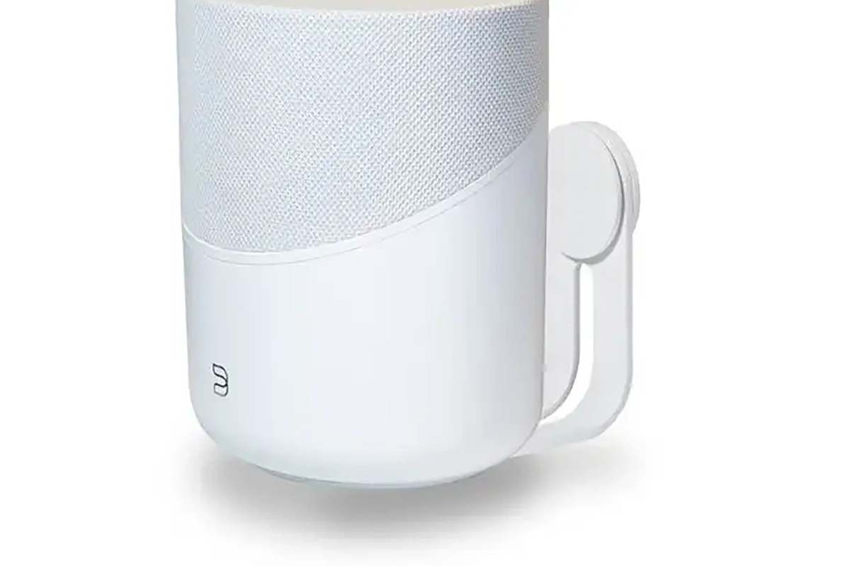White model holding a light-coloured speaker, three-quarter view
