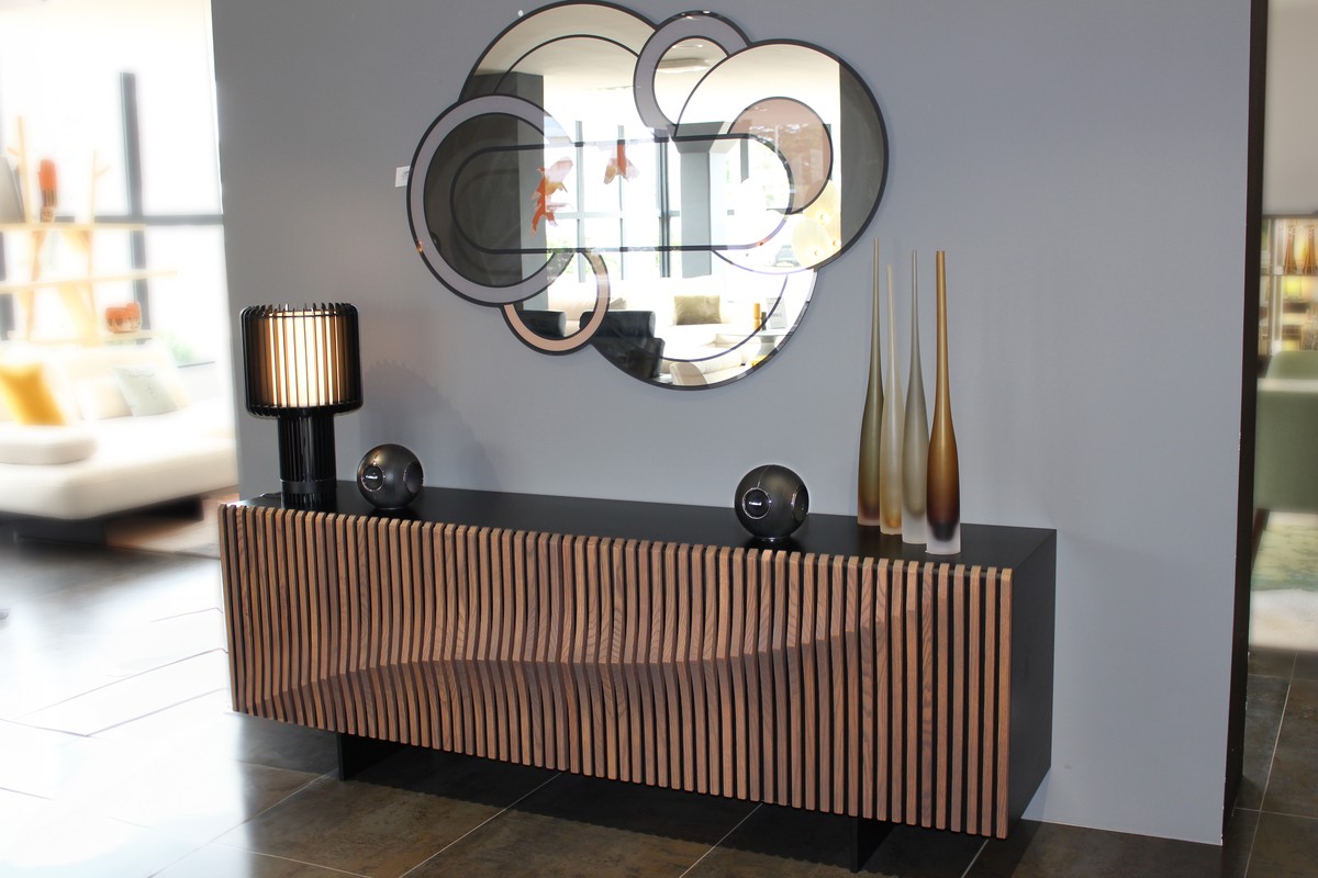 Two black spheres at each end of a slatted wooden sideboard