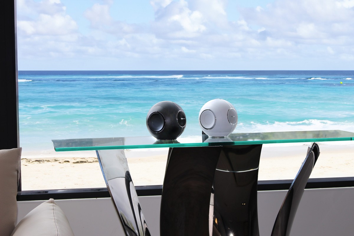 A black and a white sphere on a glass table facing the sea
