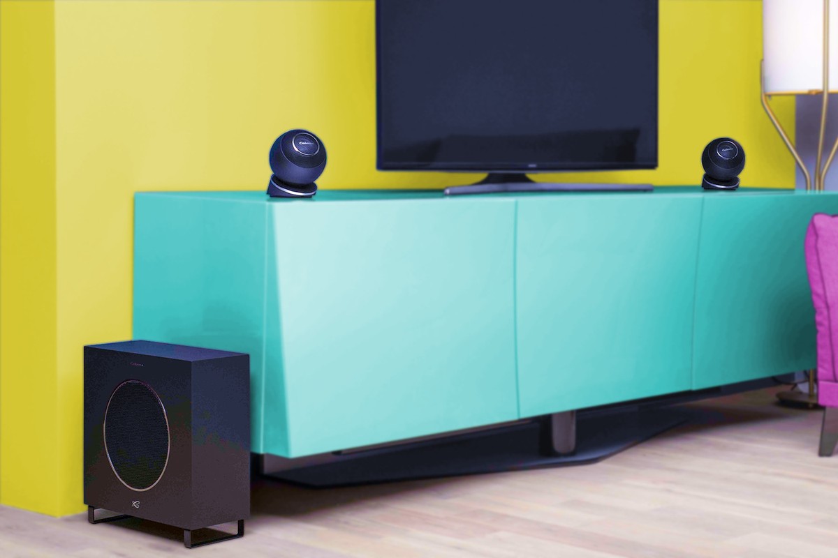 Soggiorno con pareti gialle, mobile turchese, due satelliti sferici e subwoofer nero a terra