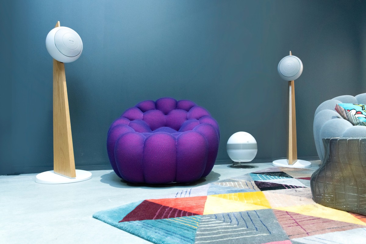 Salon bleu avec deux colonnes en chêne, un fauteuil violet et un caisson sphérique blanc