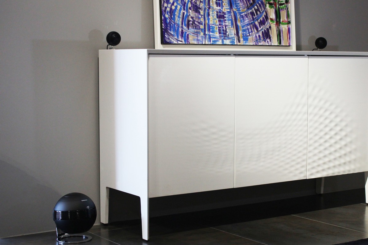 Schwarzer Subwoofer am Fuss eines weissen Sideboards, schwarze Satelliten darauf