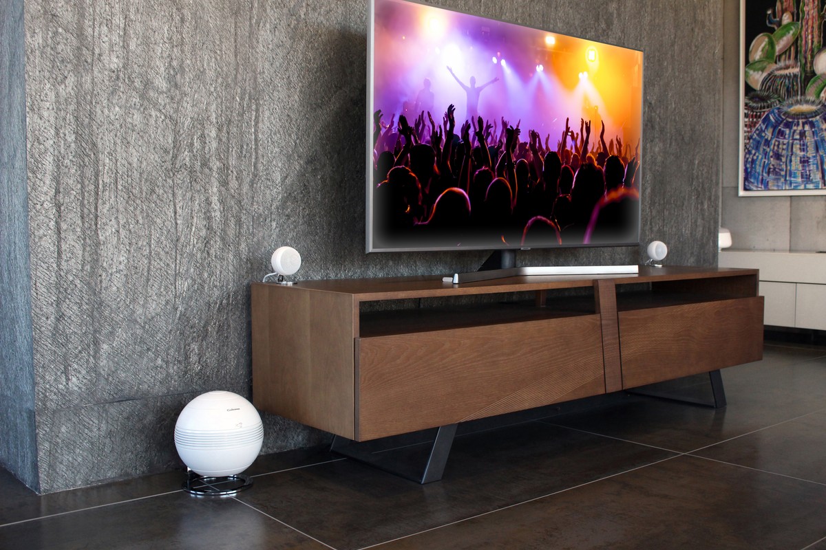 Weisses System rund um ein TV-Möbel aus Holz, Subwoofer am Boden
