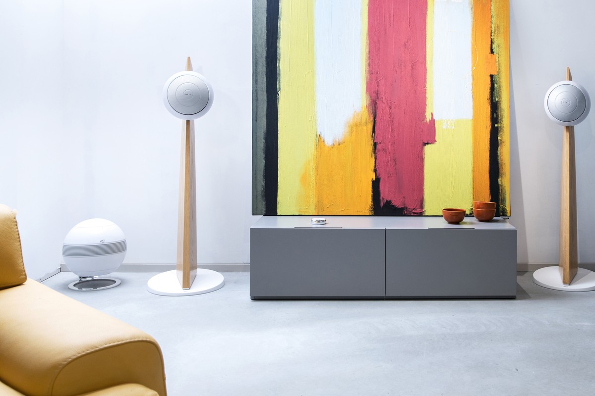 White subwoofer next to a sofa, two Baltic 5 speakers on oak stands