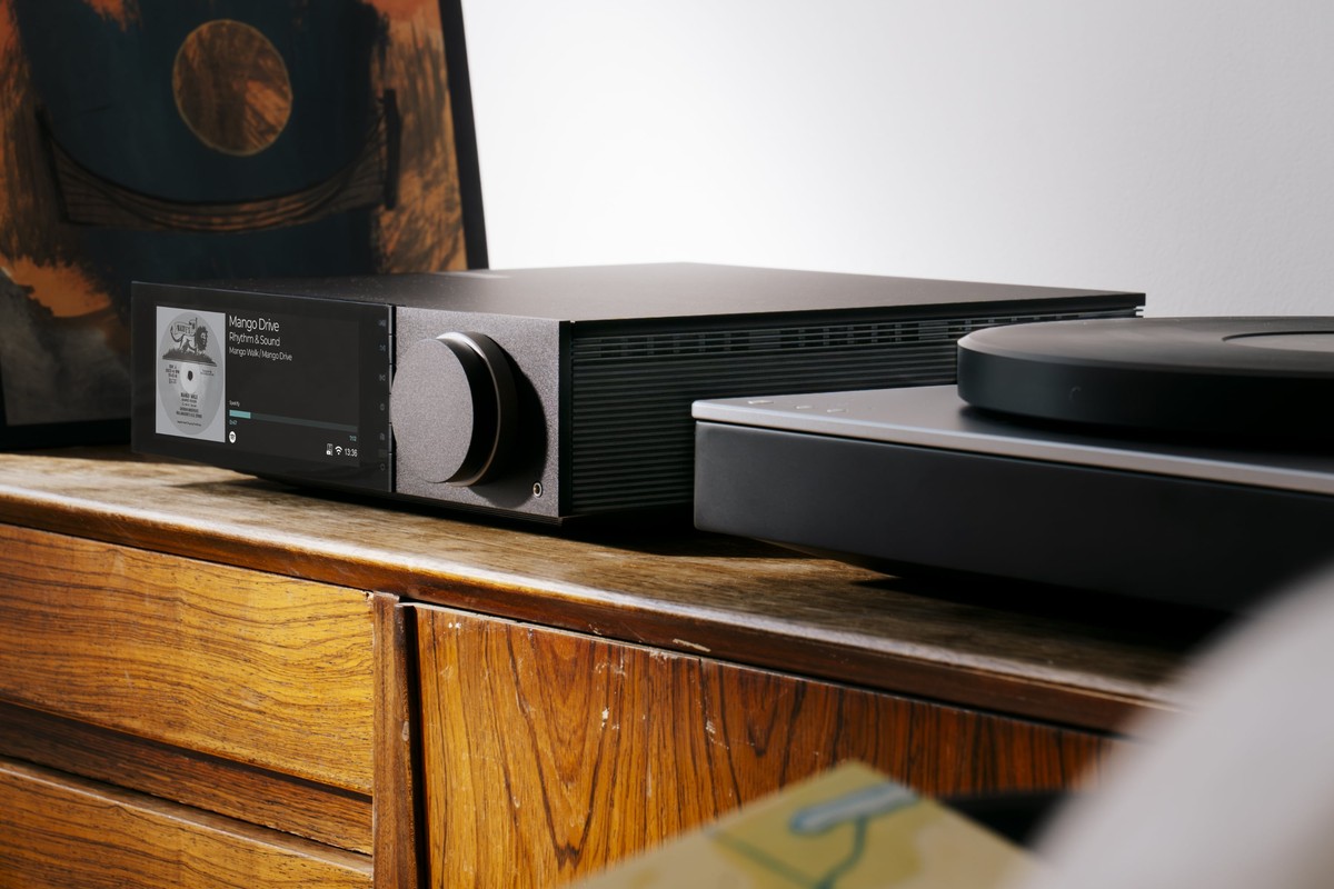 Appareil installé sur un meuble en bois, à côté d'une platine vinyle