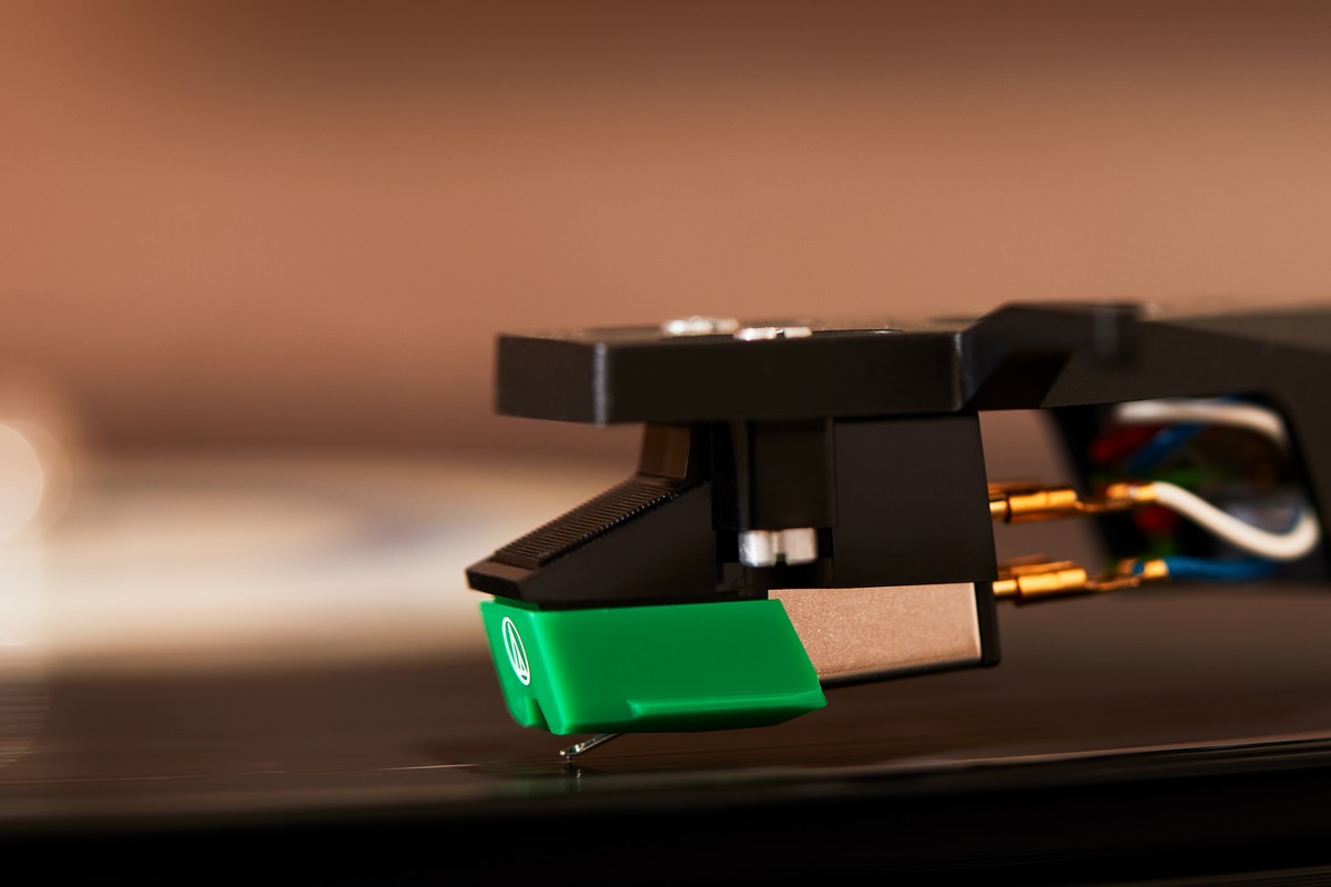Cellule à aimant mobile verte posée sur le sillon d'un disque noir