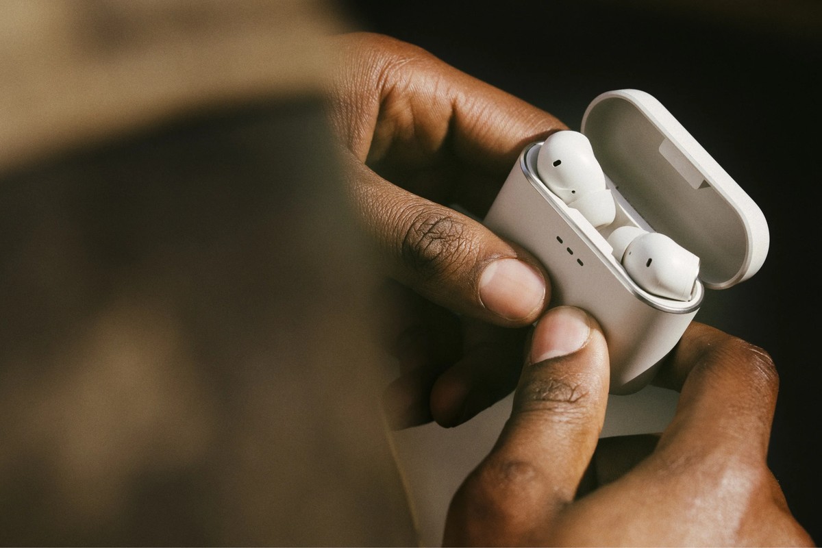 Mains ouvrant l'étui de charge blanc des écouteurs