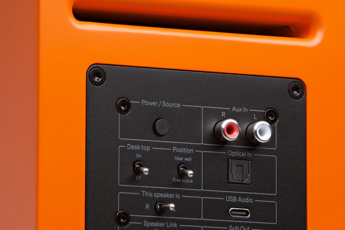 Pannello posteriore arancione di un diffusore con ingressi Aux RCA, ottico e USB Audio