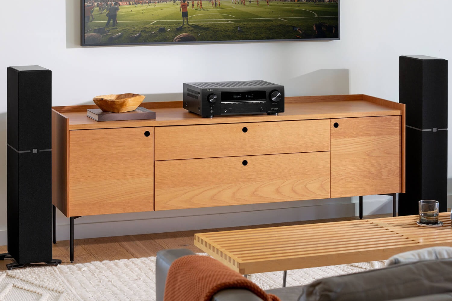 Salon home cinéma avec ampli-tuner noir sous un téléviseur et enceintes colonnes