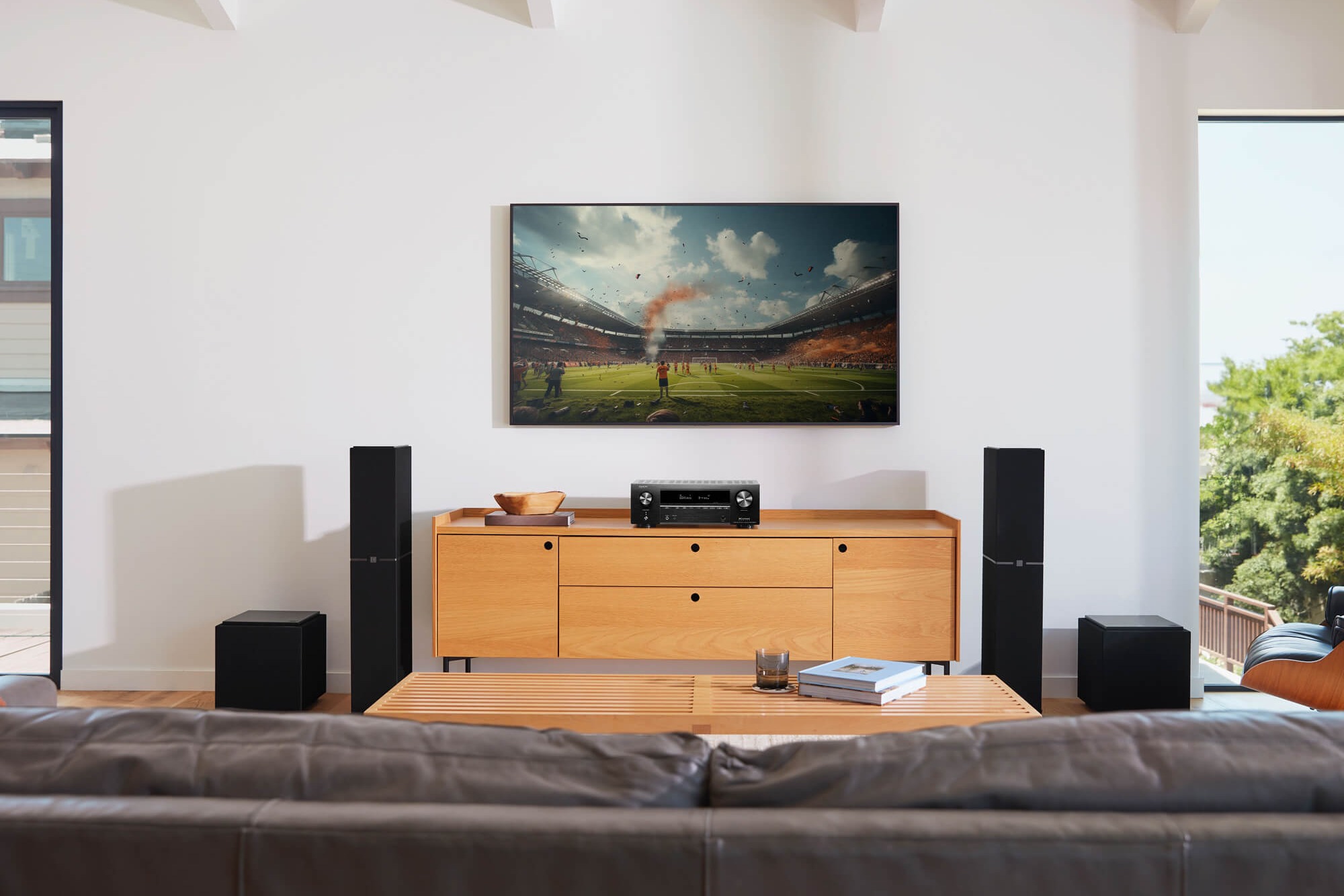 Salon vu depuis le canapé : téléviseur mural, ampli-tuner, enceintes colonnes et deux caissons