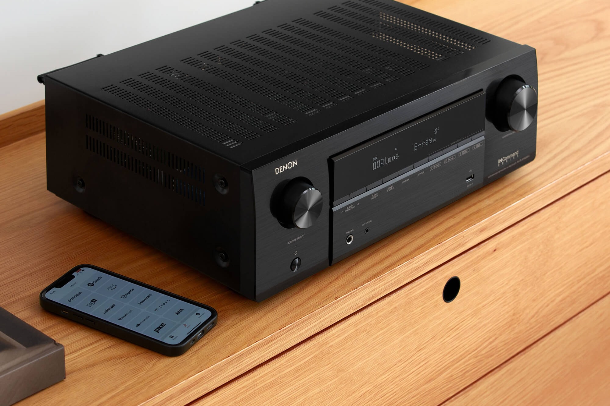Façade d'ampli-tuner noir sur un meuble, smartphone avec application de streaming
