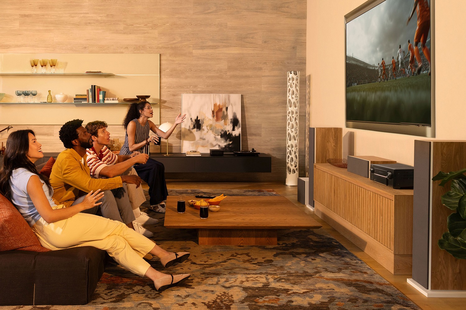 Groupe d'amis devant un match à la télévision, ampli-tuner et enceintes colonnes