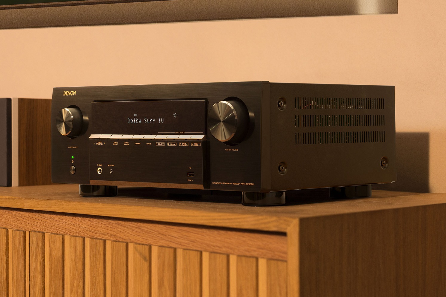 Ampli-tuner noir de près sur un meuble en bois, afficheur indiquant le mode Dolby Surround