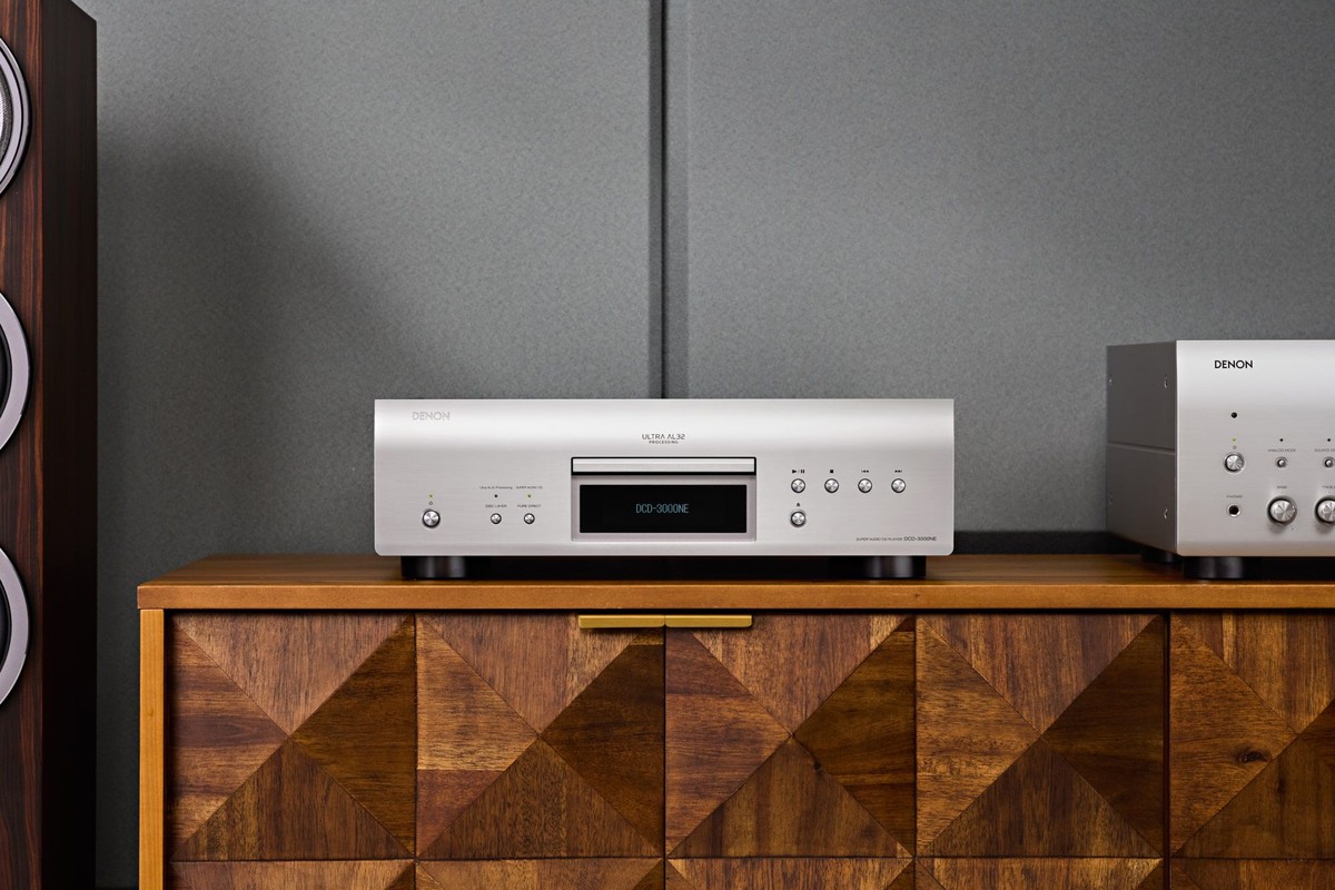 Lettore SACD argento su una credenza in legno, diffusore da pavimento a sinistra e amplificatore a destra