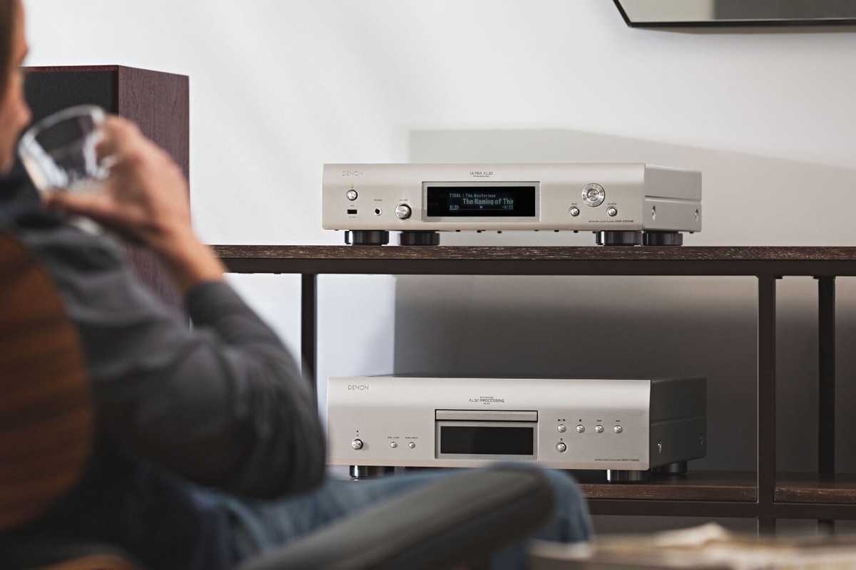 Lecteur réseau argent sur une étagère au-dessus d'un lecteur CD, auditeur au premier plan